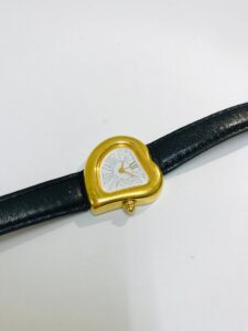 YVES SAINT LAURENTのハート型ゴールドケースと黒いレザーベルトの腕時計正面